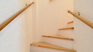 A wooden staircase with a handrail, white walls, and a textured finish. - Zennova 16 Naftilos Family Summer House (Kassandra)