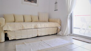 A room with a beige sofa, a white rug, a framed picture on the wall, and a window with curtains. - Zennova 16 Naftilos Family Summer House (Kassandra)