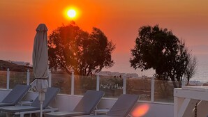 A rooftop lounge area with sun loungers and a view of the sunset over the sea. - Studio (2 adults), Marias Place Oia (Thira - Santorini)