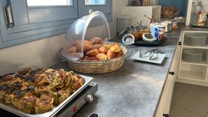 A breakfast buffet with a variety of pastries, a tray of cooked eggs, and condiments. - Studio (2 adults), Marias Place Oia (Thira - Santorini)