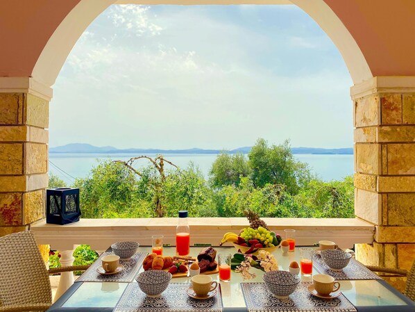 A table set with breakfast items and a view of a lake and mountains.