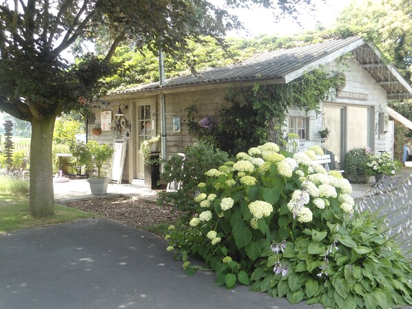 A stone building with a tiled roof, a garden with hydrangeas, and a sign reading "PASSE & PARTOUTAGE". - Country-Style Cottage (Beernem)
