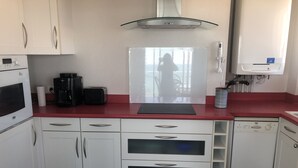 Een keuken met witte kasten, een rode aanrecht, een koffiezetapparaat, een broodrooster en een vaatwasser.