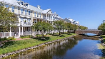 A row of waterfront buildings with balconies, a stone bridge, and a calm waterway.