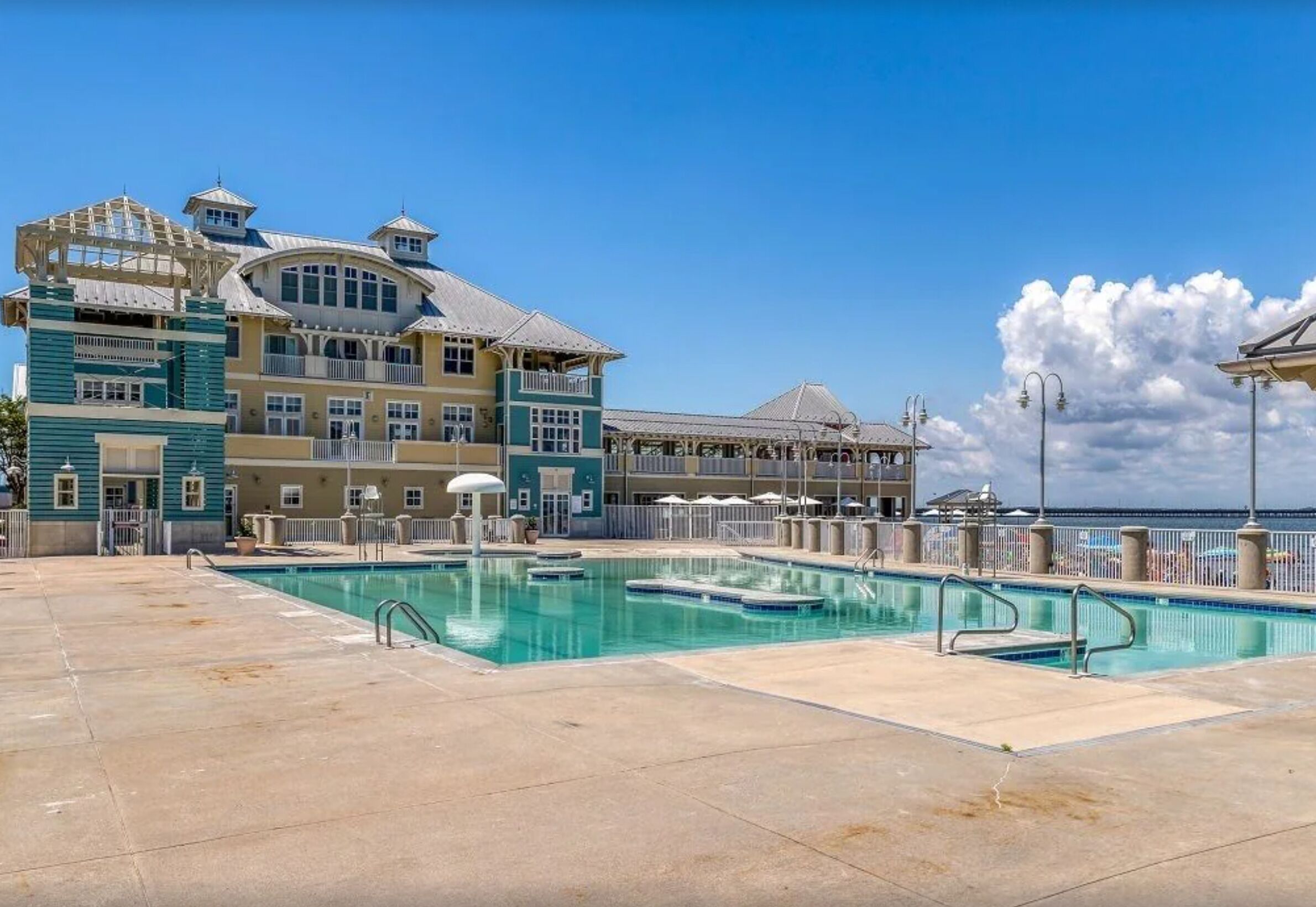 Un grand complexe hôtelier doté d’une piscine, de nombreux balcons et offrant une vue sur l’océan.