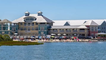 A waterfront hotel with multiple buildings, a beach area, and umbrellas.