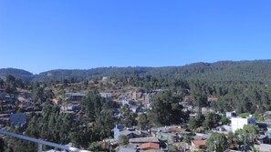 Eine Stadt mit einer Mischung aus Wohn- und Geschäftsgebäuden, umgeben von Hügeln und dichten Wäldern.