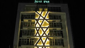 A multi-story building with a distinctive geometric facade and illuminated windows at night.