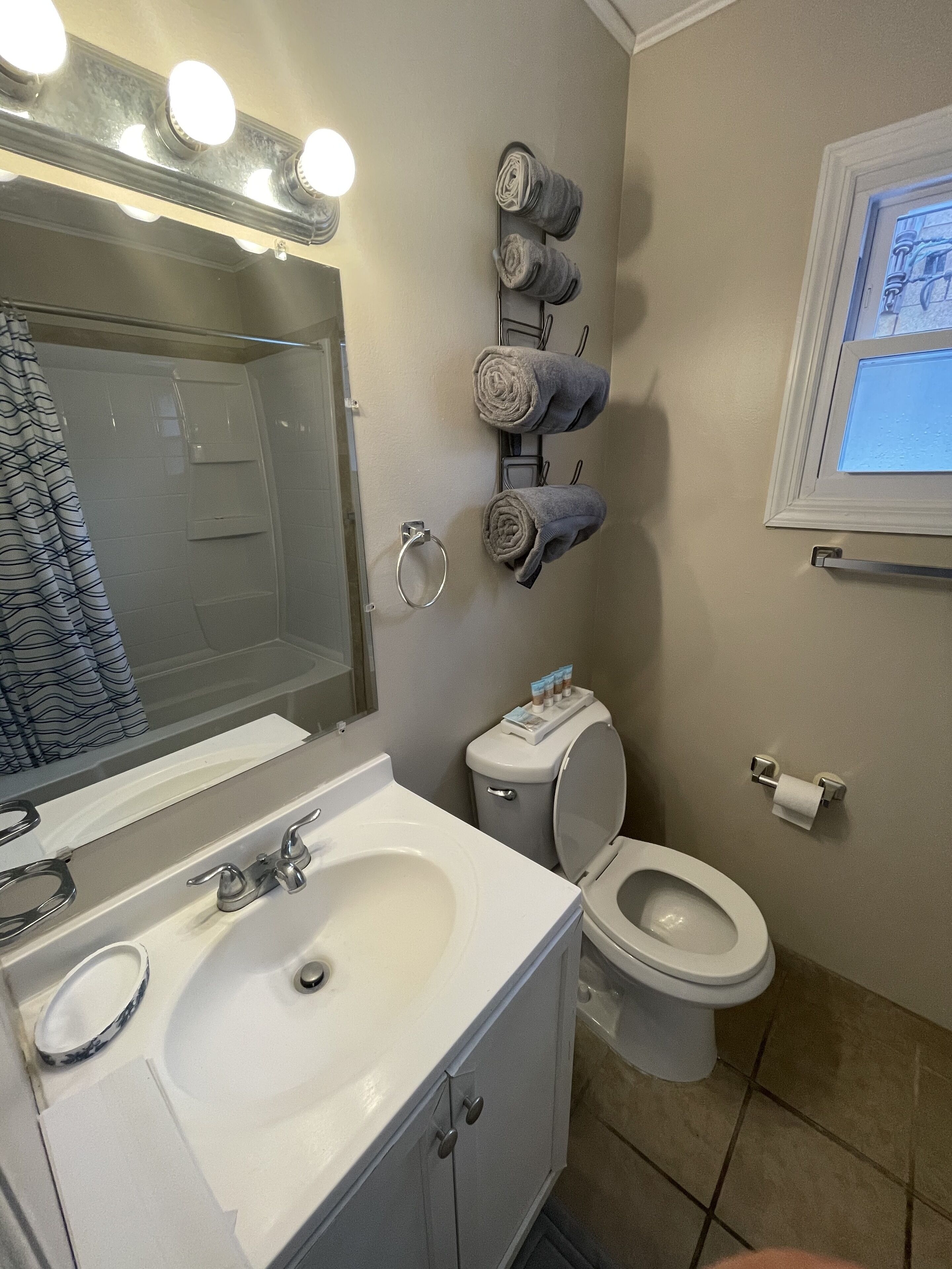 Een bad/douchecombinatie, een haardroger, handdoeken, toiletpapier