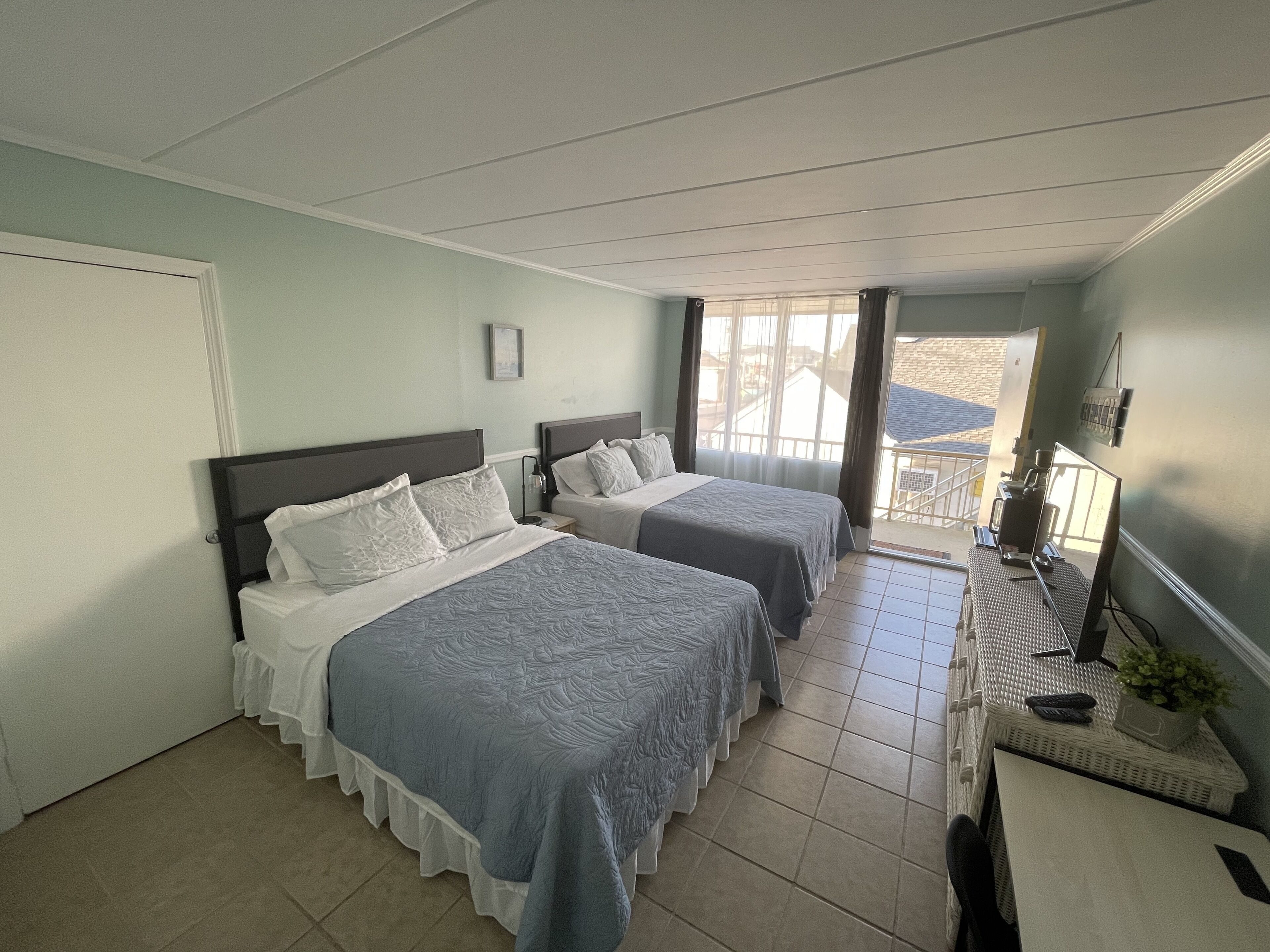 Ein Hotelzimmer mit zwei Betten, einem Schreibtisch mit Computer und Blick ins Freie.