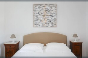 Een slaapkamer met een bed, twee nachtkastjes en een abstract schilderij aan de muur.