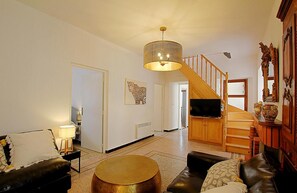 Een ruime woonkamer met een trap, een televisie en een luipaard kunstwerk aan de muur.