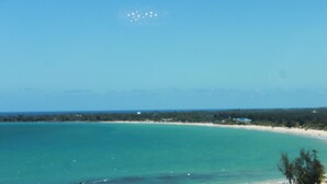 A beach view with clear turquoise water, a sandy shore, and palm trees. - JR ONE BR ESJ TOWERS! HIGH FLOOR,VIEW LOCATION! (Carolina)