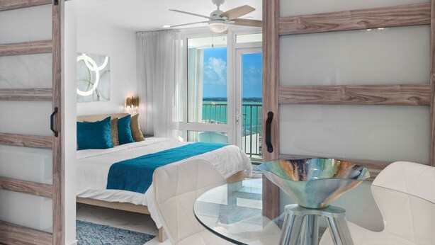 A modern bedroom with a bed, a glass table, and a balcony with a view. - JR ONE BR ESJ TOWERS! HIGH FLOOR,VIEW LOCATION! (Carolina)