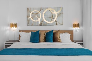 Una cama bien hecha con una colcha azul, un cabecero y una obra de arte en la pared.