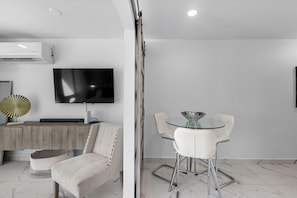 Una sala de estar moderna con un sofá, una mesa de vidrio y un televisor montado en la pared.