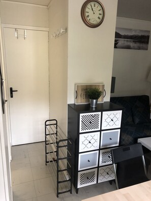 A room with a white door, a black and white patterned cabinet, a clock on the wall, and a black chair. - Apt private residence close to all amenities and leisure facilities (La Bourboule)