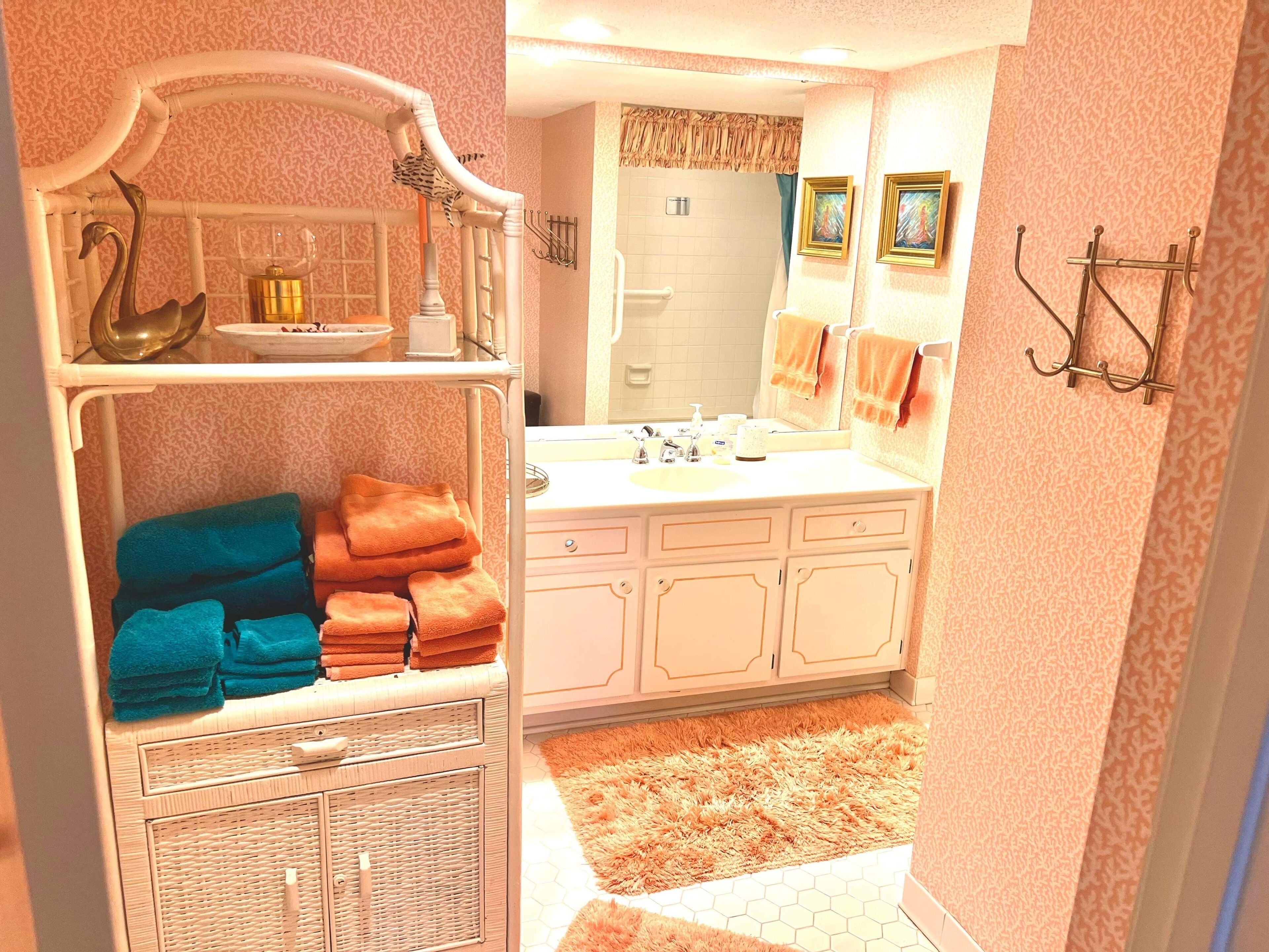 Une salle de bain avec un meuble-lavabo, un évier et un miroir. On y trouve des serviettes et des articles de toilette sur le meuble-lavabo.