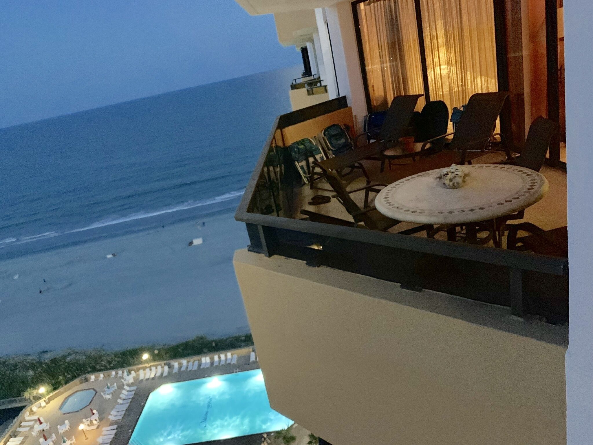 A balcony with a view of the beach and a pool area.