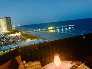 A balcony with a view of the beach, a pier, and a cityscape at night. - Maisons Sur Mer -Oceanfront Luxury (Myrtle Beach)