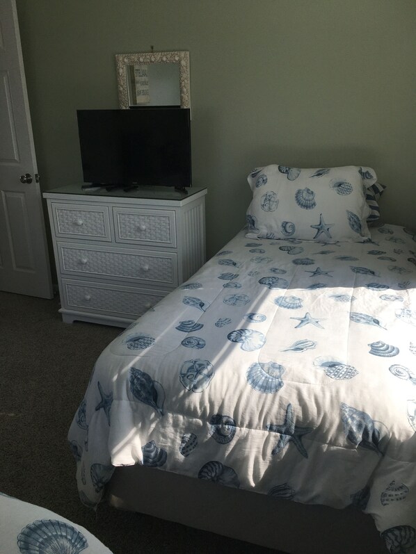Une chambre à coucher avec un lit, une commode et un téléviseur.