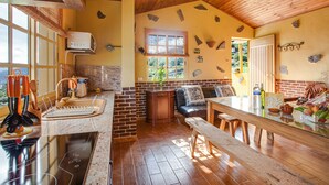A kitchen with a wooden ceiling, stone wall accents, a dining area with a bench, and a view through a window. - Vacation Home Casa La Chocita with Sea View, Mountain View (Los Realejos)