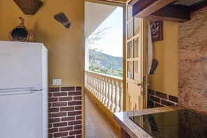 A kitchen with a refrigerator, a stove, a brick wall, and a balcony with a railing. - Vacation Home Casa La Chocita with Sea View, Mountain View (Los Realejos)
