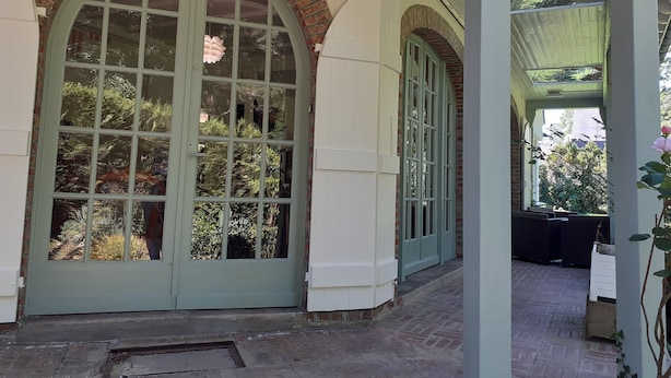 Un portico coperto con un'ampia porta ad arco e una porta più piccola, entrambe con pannelli di vetro.