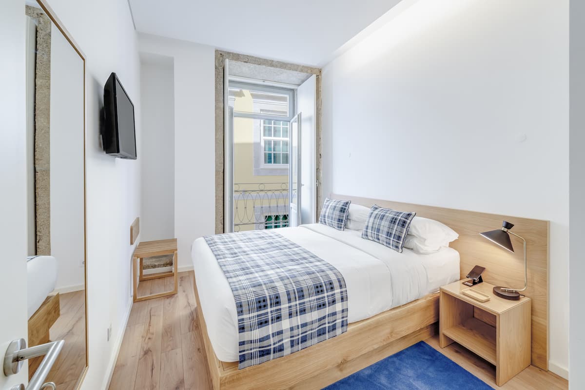 Une chambre moderne avec un lit en bois, une table de chevet avec une lampe et un téléviseur fixé au mur.