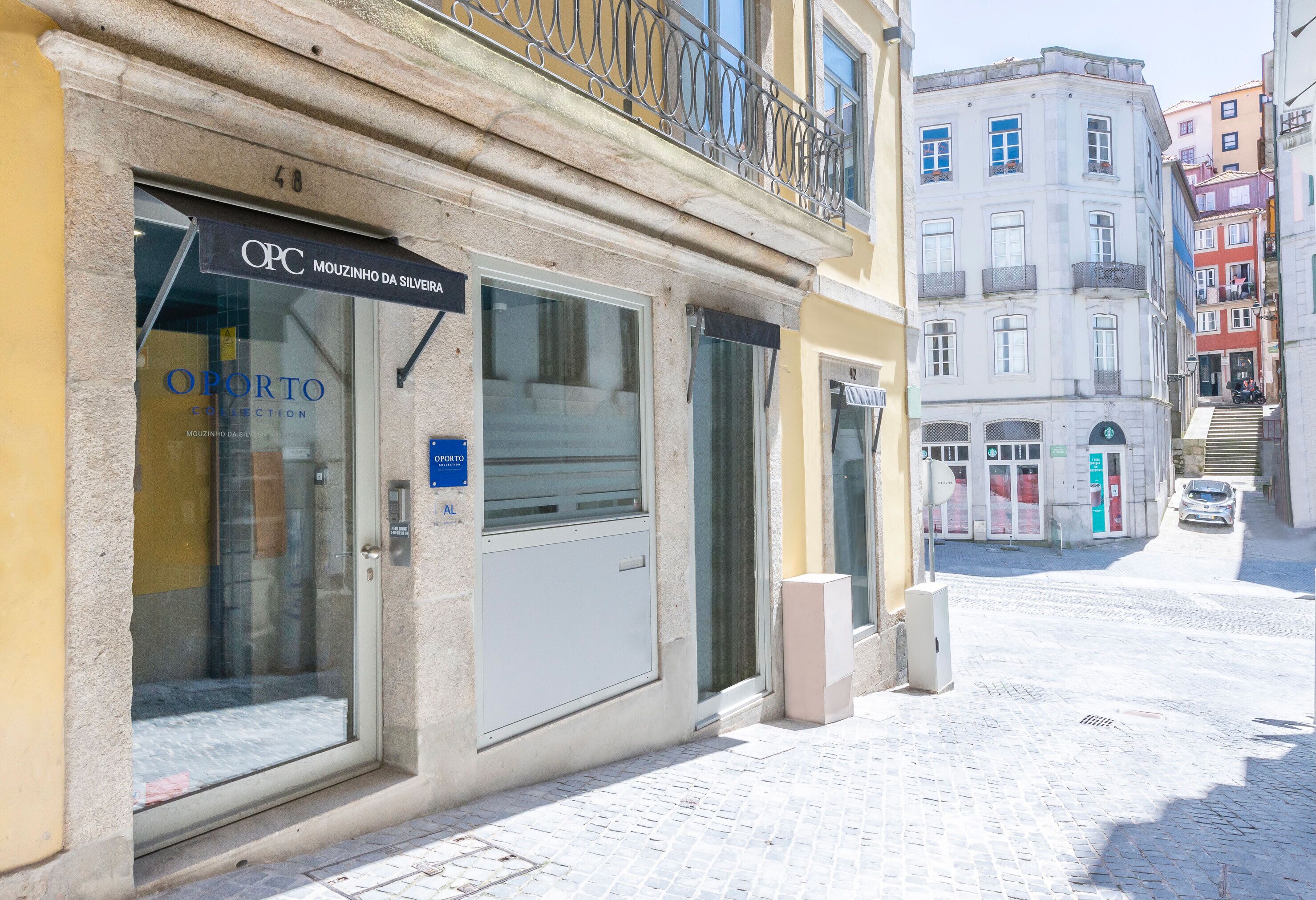 A building with a storefront labeled "OPC MOUZINHO DA SILVERA" and a visible entrance door.