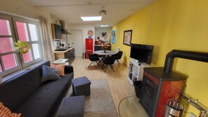 Un espace de vie compact comprenant un canapé, une table à manger, des chaises, un téléviseur et une cheminée.