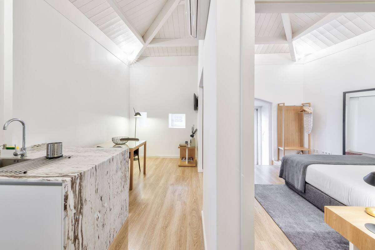 Une pièce moderne et minimaliste avec un coin cuisine doté d’un plan de travail en marbre et d’une table à manger en bois.