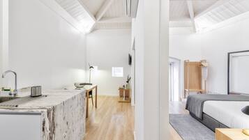 A modern, minimalist room with a kitchen area featuring a marble countertop and a wooden dining table.