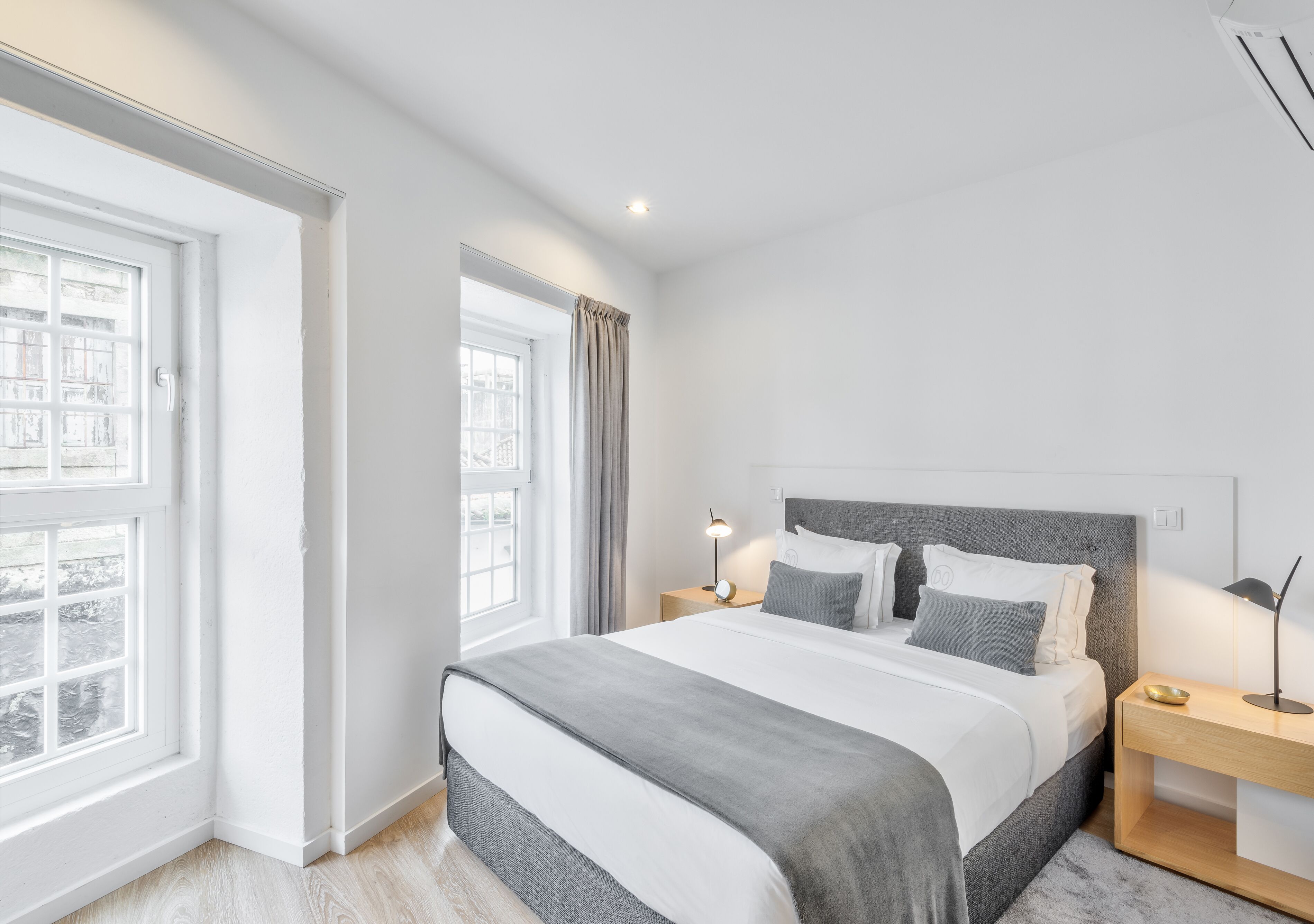 Una camera da letto moderna con un letto grande, comodini, una finestra e vista sugli edifici.