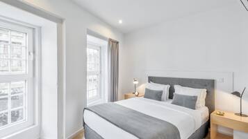 Una camera da letto moderna con un letto grande, comodini, una finestra e vista sugli edifici.