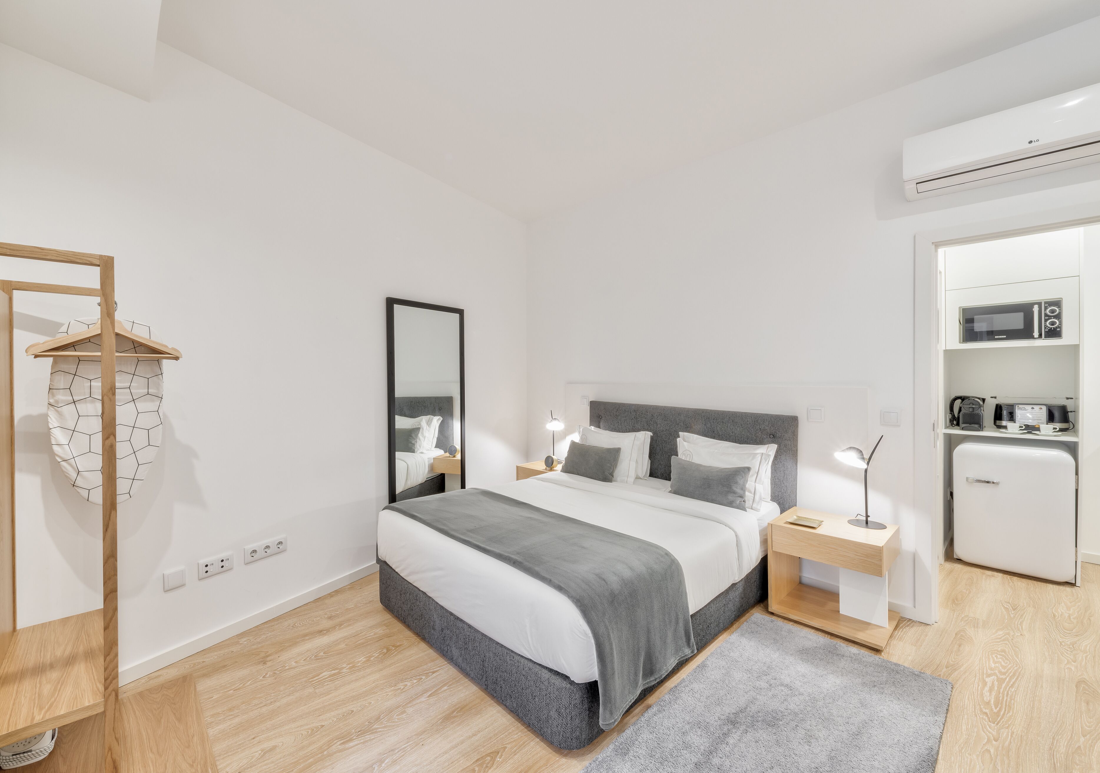 Une chambre moderne comprenant un lit, des tables de chevet, une armoire et un coin cuisine.