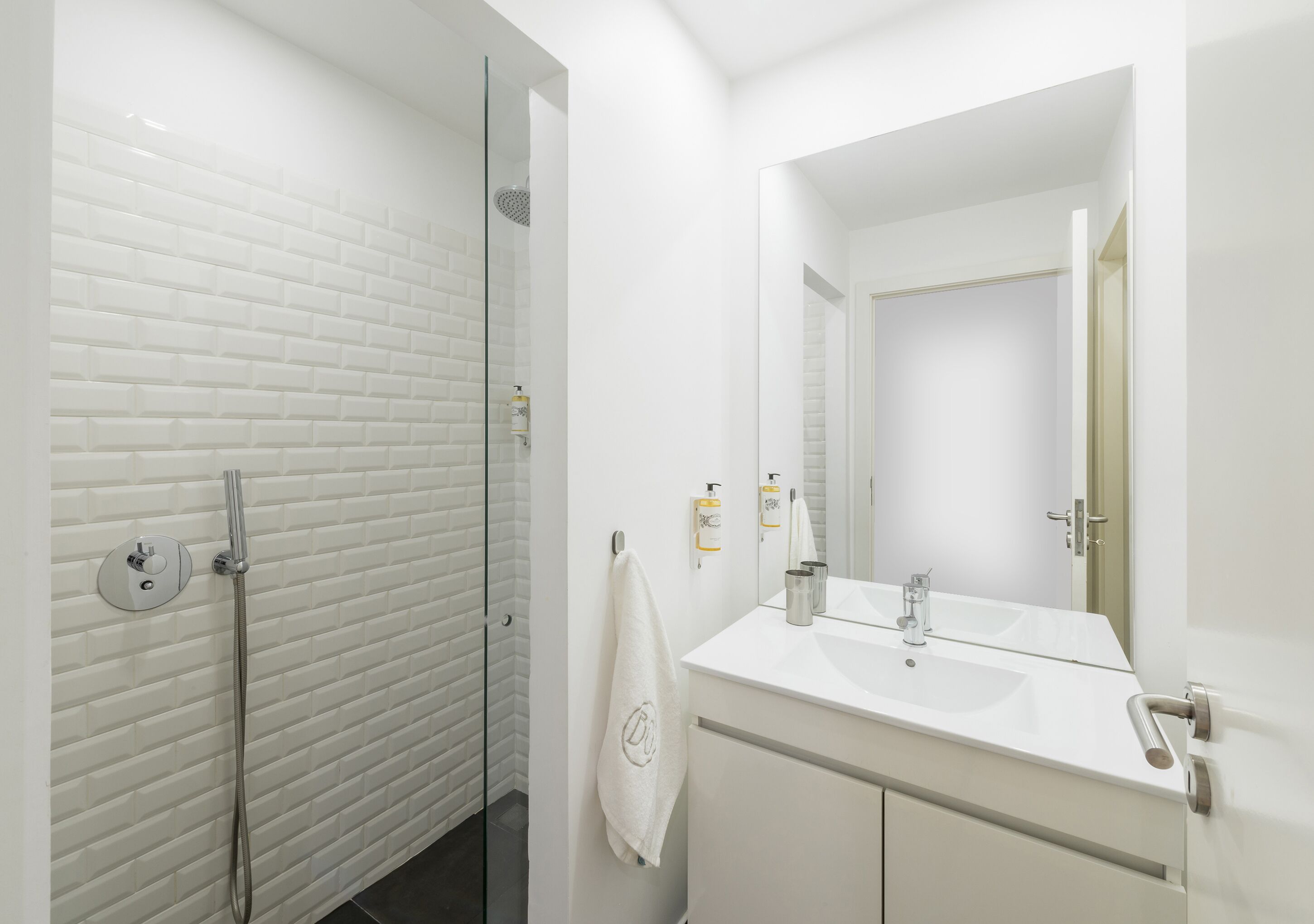A modern bathroom with a glass shower enclosure, a white sink, and a mirror.