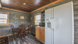 Eine rustikale Küche mit Holzschränken, einem weißen Kühlschrank und einem Esstisch mit Stühlen.