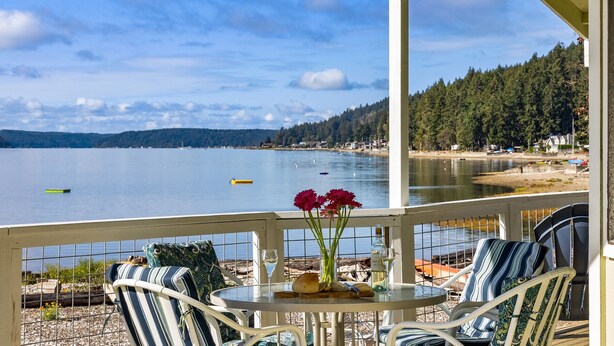 A balcony with a table, chairs, and a vase with flowers. - Hood Canal Beach house, Low bank waterfront,  enjoy nature from your deck (Belfair)