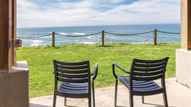An open doorway leading to a grassy area with two chairs facing the ocean. - Depoe Bay Oceanfront Condo/Resort, Great Views!!(Nights 5, 6, & 7 only $50 each) (Depoe Bay)