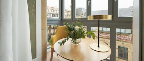 A room with a round wooden table, a yellow chair, and a vase with flowers.