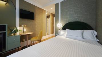 A hotel room with a bed, a desk, a chair, a TV, and a bathroom visible through an open door.