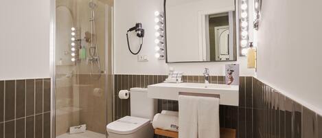 A modern bathroom with a glass-enclosed shower, a white toilet, a vanity with a mirror and lights, and two towels hanging on a rack.