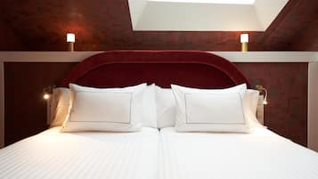 A bed with white linens and a red headboard, two bedside lamps, and a skylight above.