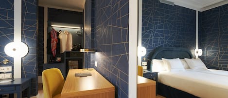 Una habitación de hotel con escritorio, silla y cama con dos almohadas.