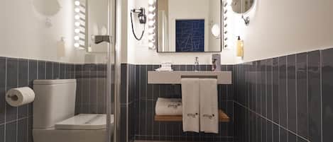 Un baño moderno con inodoro, lavabo, espejo y tocador con perchero.