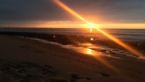 A beach with a sunset, rocky shoreline, and calm sea. - Villa del Sol Mancora (Máncora)