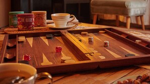 A mahjong table with tiles and cups, a piano, a lamp, and a chair in a warmly lit room. - Villa del Sol Mancora (Máncora)