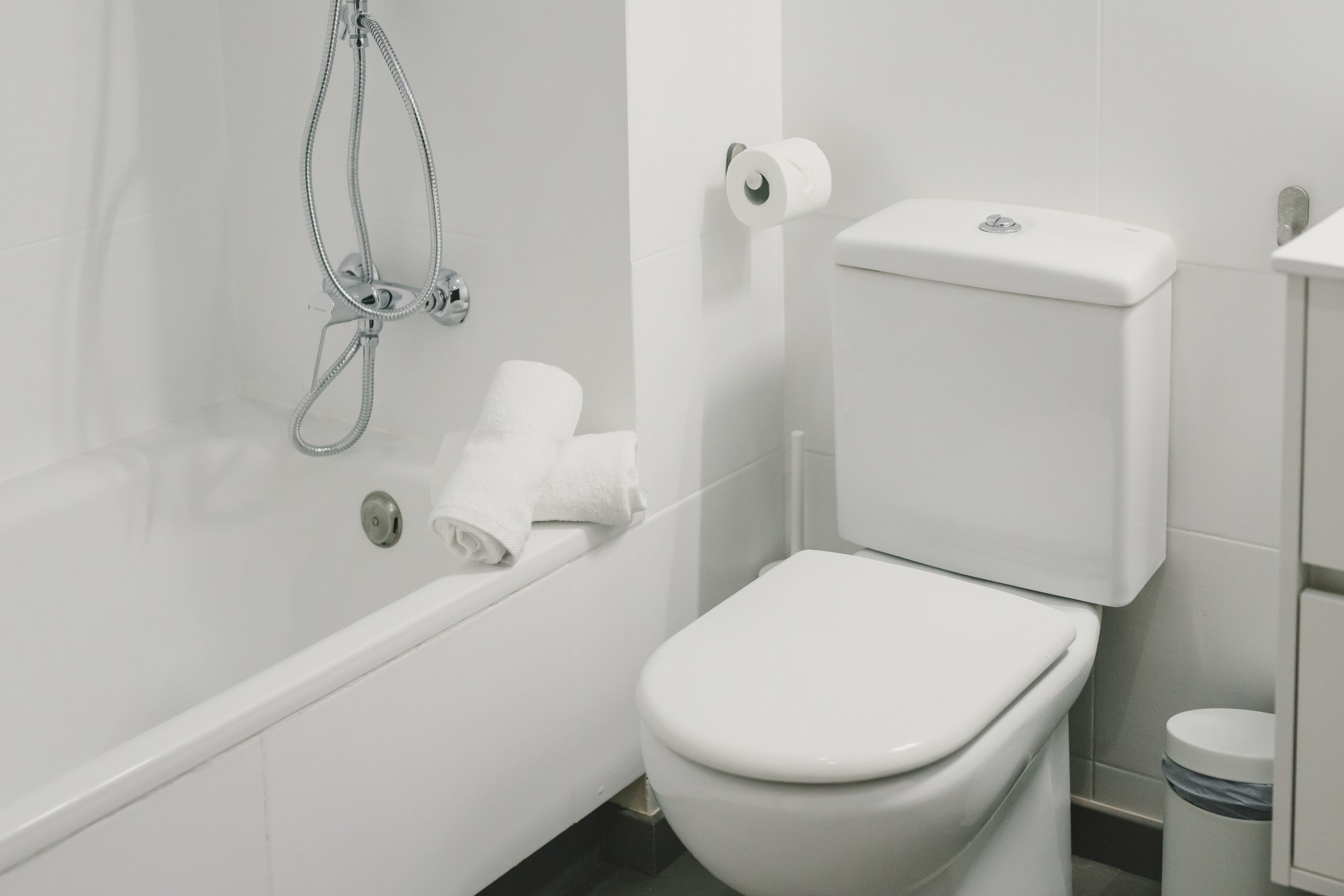 A modern bathroom with a white bathtub, toilet, and sink.