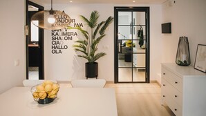A modern dining area with a white table, chairs, and a potted plant.
